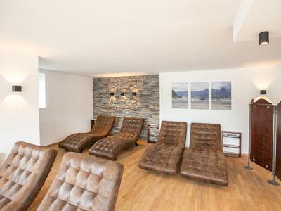 Jasne pomieszczenie spa z wygodnymi brązowymi leżakami i drewnianą podłogą.