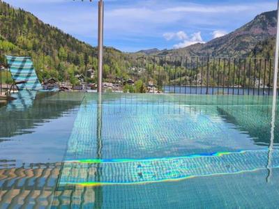 Basen z widokiem na góry, drewniany pomost i kilka krzeseł w słoneczną pogodę.