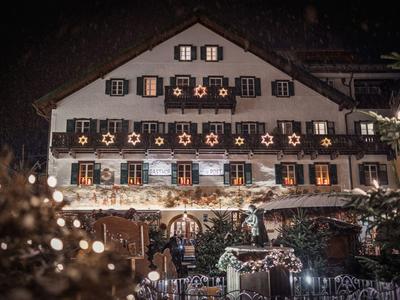 Traditionelles Gasthaus mit dekorierten Fenstern und warmem Licht in der Nacht.