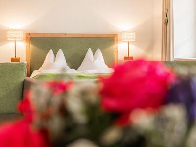 Gemütliches Hotelzimmer mit grünem Bettkopfteil und zwei Nachtlampen.