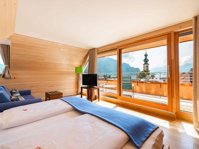 Modernes Hotelzimmer mit großem Bett, Holzverkleidung und Panoramafenster mit Bergblick.