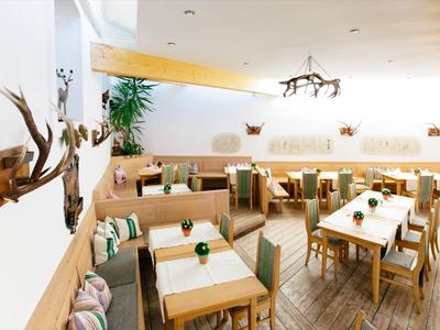 Helles, modernes Restaurant mit Holzmöbeln, grünen Akzenten und bequemen Sitzbereichen.