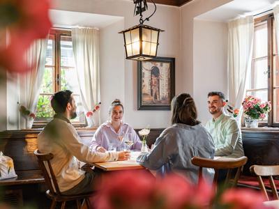 Vier Personen sitzen in einem gemütlichen Hotelrestaurant und unterhalten sich entspannt.