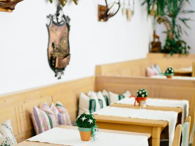 Holztische mit weißen Läufern und Topfpflanzen in einem gemütlichen Restaurant mit Hirschgeweihen.