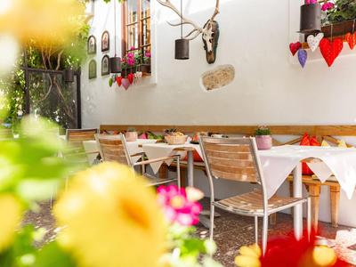 Gemütlicher Außenbereich eines Hotels mit gedeckten Tischen und Blumenarrangements.