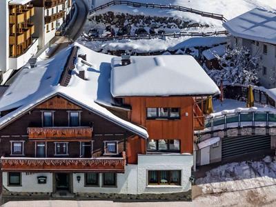 Sneeuwbedekt hotel met rustiek houten ontwerp en terras in een bergresort.