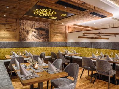 Cozy hotel dining room with wooden walls, upholstered chairs, and decorative elements.