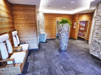 Modern, cozy hotel waiting area with wooden walls, two chairs, and a large vase.