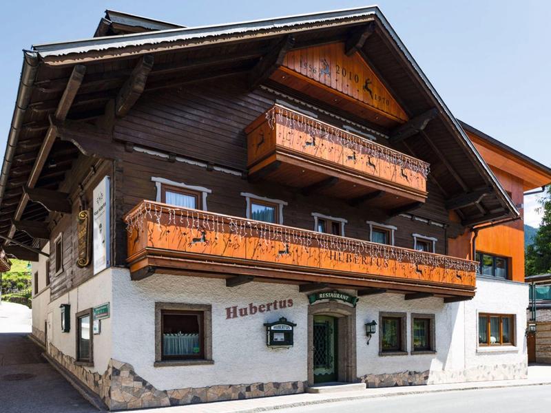 Traditional chalet with wooden cladding and decorative balconies in a mountain village.