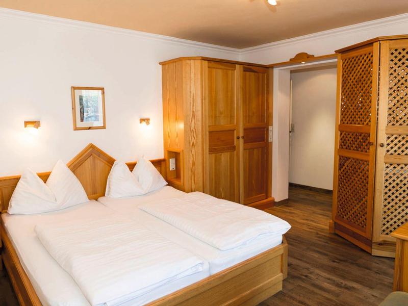 Cozy hotel room with double bed, wooden wardrobe, and neutral walls.