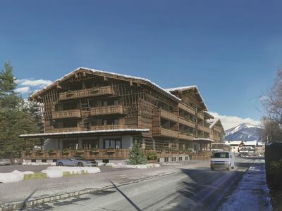Groot houten hotel in alpine omgeving met besneeuwde bergen op de achtergrond.