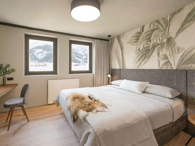 Camera d'hotel moderna con grande letto matrimoniale, sedia, piante e decorazioni murali con foglie.