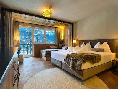 Camera d'hotel moderna con letto matrimoniale, grande finestra e luce calda.