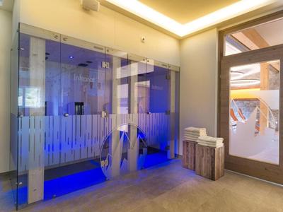 Moderner Wellnessbereich mit beleuchteter Sauna und Holzbank im Hotel.