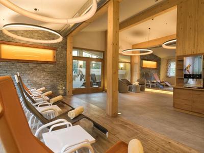 Moderner Wellnessbereich mit Liegestühlen, Holzboden und großen Glasfenstern.