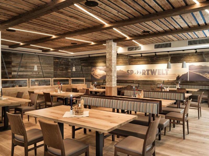 Rustikales Restaurant mit Holztischen, Stühlen und warmem Beleuchtungskonzept.