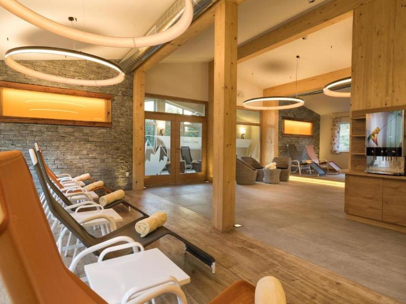 Moderner Wellnessbereich mit Liegestühlen, Holzboden und großen Glasfenstern.