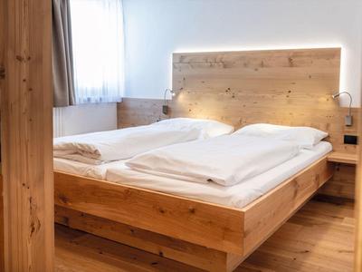 Gemütliches Schlafzimmer mit Holzbettrahmen und weißen Bettdecken in hellem Raum.