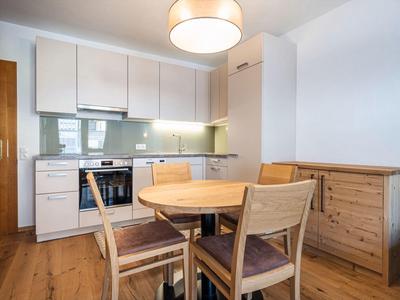 Moderne keukenhoek met houten eettafel en vier stoelen in een lichte kamer.