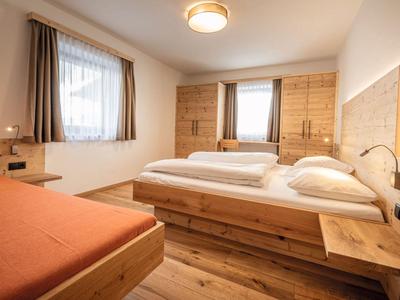 Helles Hotelzimmer mit zwei Einzelbetten, einem zusätzlichen Bett und Holzmöbeln.