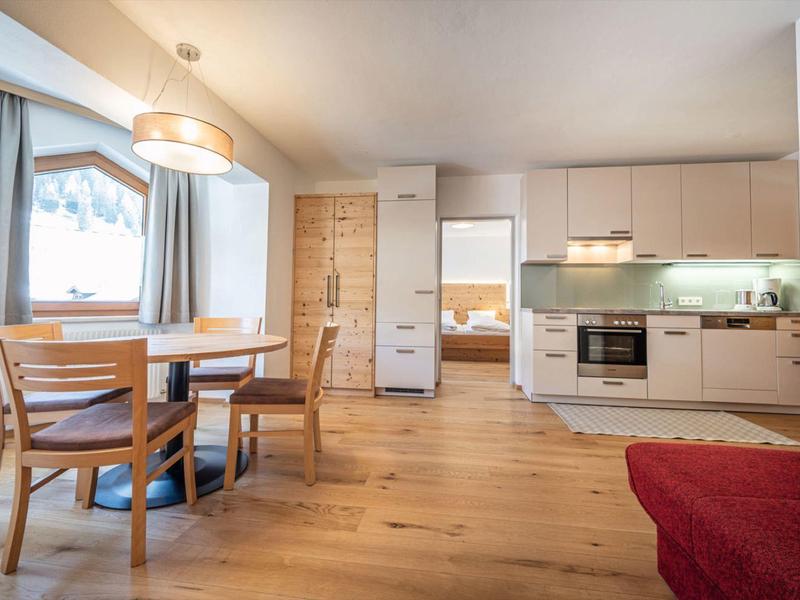 Helle Küche und Essbereich mit Holzmöbeln und Parkettboden in moderner Ferienwohnung.