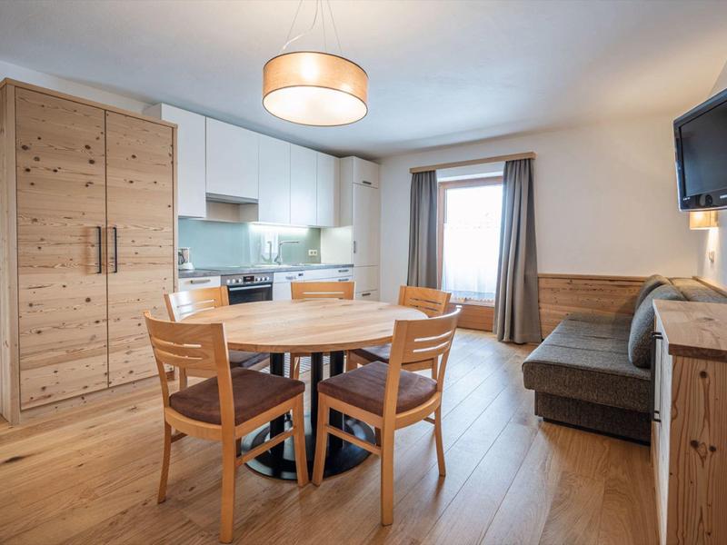 Moderner Wohn- und Essbereich mit Holzmöbeln, Sofa, Esstisch und Fernseher in einem hellen Raum.