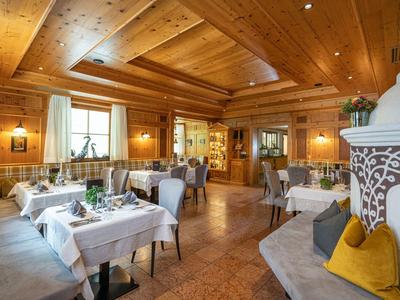 Gemütliches Restaurant mit Holzwänden, weißen Tischdecken und Sitzbänken mit farbigen Kissen.