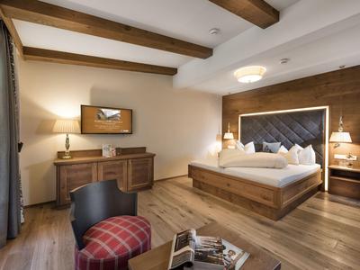 Modernes Schlafzimmer mit Holzboden, Doppelbett, Schreibtisch und großen Fenstern.