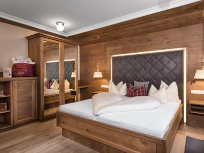 Gemütliches Hotelzimmer mit Holzmöbeln, großem Bett und Spiegelkleiderschrank.