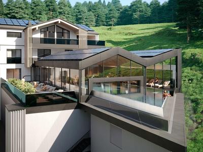 Moderner Gebäudekomplex mit großen Glasfenstern und begrüntem Dach in ländlicher Umgebung.