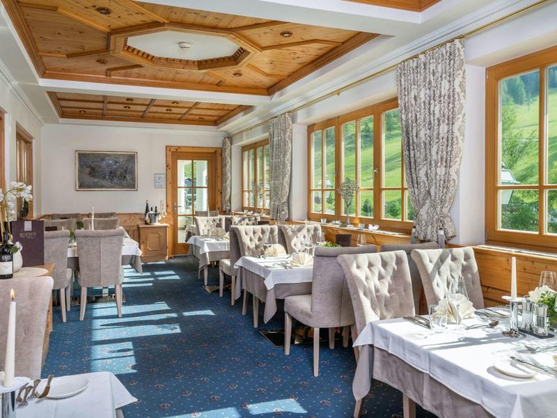 Hell eingerichteter Speiseraum mit Fensterblick auf grüne Hügel.