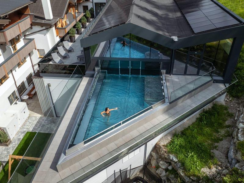 Ein moderner Außenpool auf einer erhöhten Terrasse eines Hotels mit bergiger Landschaft.