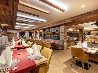 Innenansicht eines modernen, rustikalen Restaurants mit Holzbalken und gedeckten Tischen.