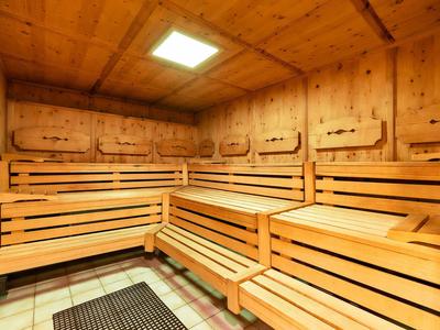 Innensauna mit mehrstufigen Holzbankreihen und Holzwänden unter einer Deckenlampe.