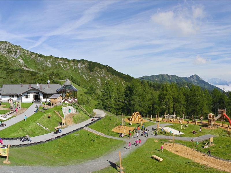 Berglandschaft mit Kinderspielplatz und Gebäuden unter klarem Himmel