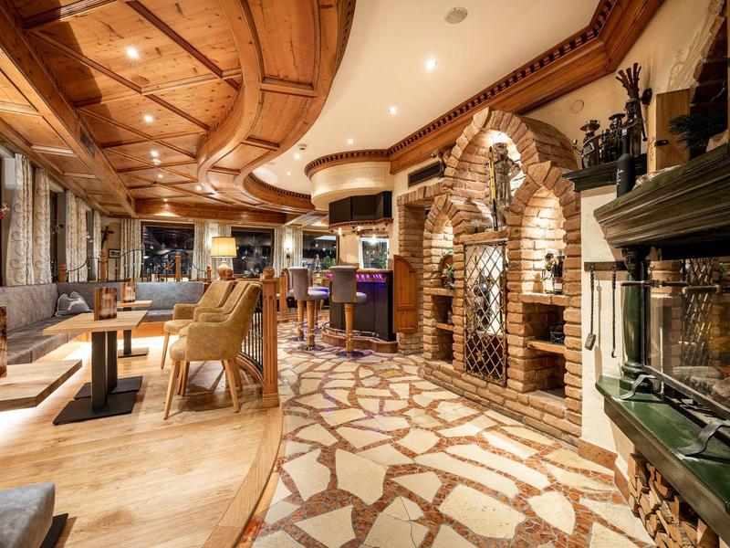 Gemütliche Hotelbar mit Holzdecke, Kamin, Sitzbereich und Bar in warmen Tönen.