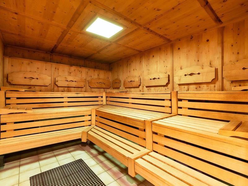 Innensauna mit mehrstufigen Holzbankreihen und Holzwänden unter einer Deckenlampe.