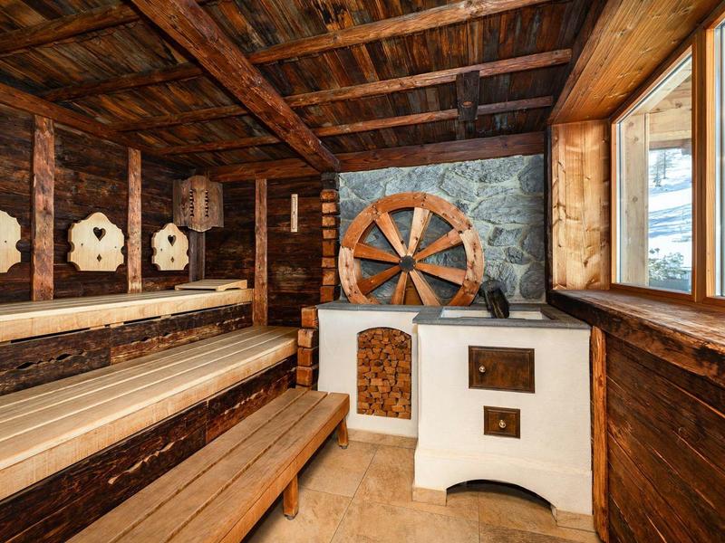 Gemütlicher Holzsauna mit Ofen, Holzbank und Fenster mit Blick nach draußen.