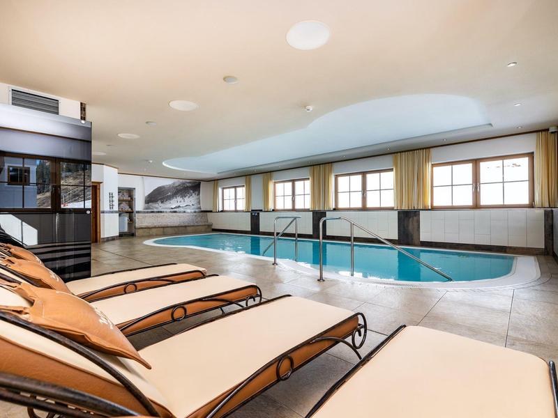 Innenhallenbad mit Liegestühlen und großen Fenstern in einem Hotel.