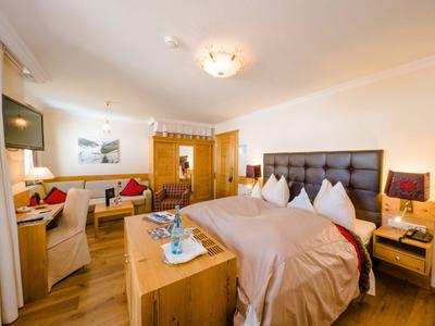 Helles, gemütliches Hotelzimmer mit Doppelbett, Sitzecke und Holzmöbeln.