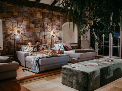 Gemütliches Wohnzimmer mit Steingewölbewand, Sofas und warmem Licht.