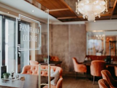 Gemütlicher Lounge-Bereich mit gemütlichen Sesseln und Holzdeckenbeleuchtung.