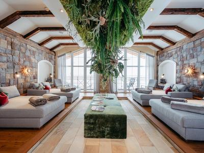 Eleganter Hotellobby mit hoher Decke, großen Fenstern und moderner Sitzgruppe mit Pflanzenakzent.