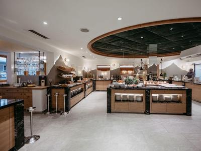 Großer Buffetbereich in modernem Hotel mit Theken, warmen Holzakzenten und Beleuchtung.