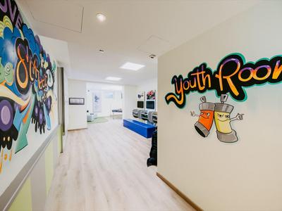 Heller Flur mit moderner Kunst und Beschilderung zum Jugendzimmer in einem Hotel.