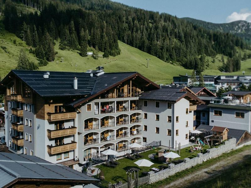 Hotel in einem idyllischen Bergtal mit Sonnenterrasse und umgeben von Wiesen und Wäldern.