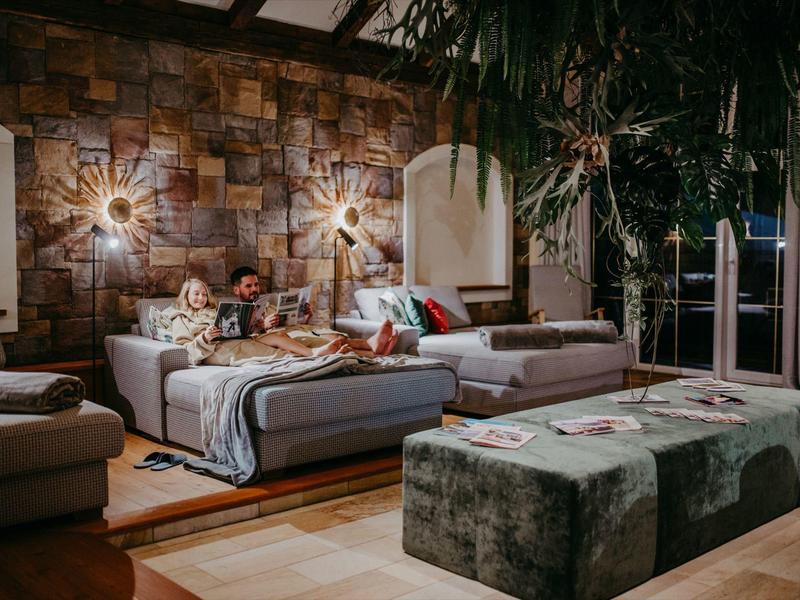 Gemütliches Wohnzimmer mit Steingewölbewand, Sofas und warmem Licht.