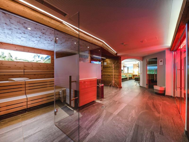 Moderner Wellnessbereich mit Sauna, Sitzbänken und roter Beleuchtung.