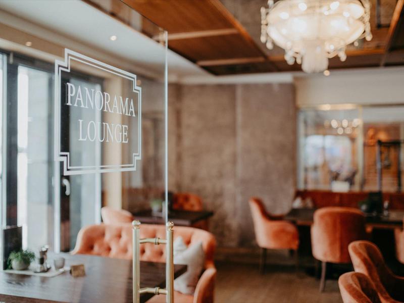 Gemütlicher Lounge-Bereich mit gemütlichen Sesseln und Holzdeckenbeleuchtung.