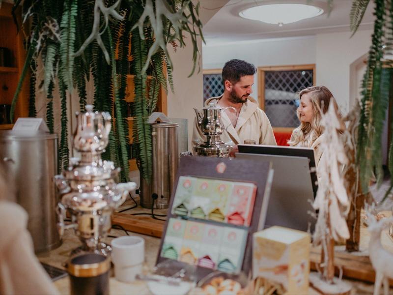 Ein Paar steht an einer Theke in einem gemütlichen, dekorierten Raum mit Pflanzen.